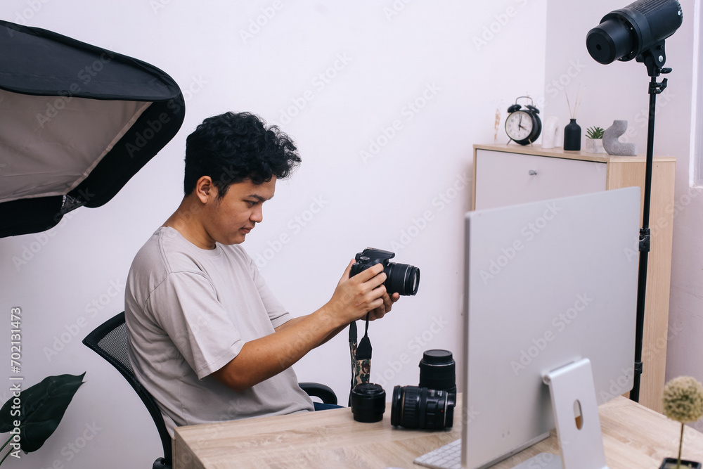 Young man photographer sitting and take a shoot with professional camera at home office studio.