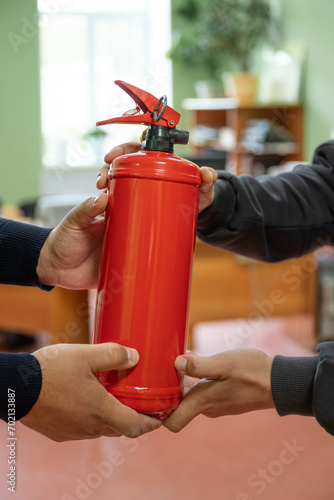 Employees are holding a fire extinguisher in the office.