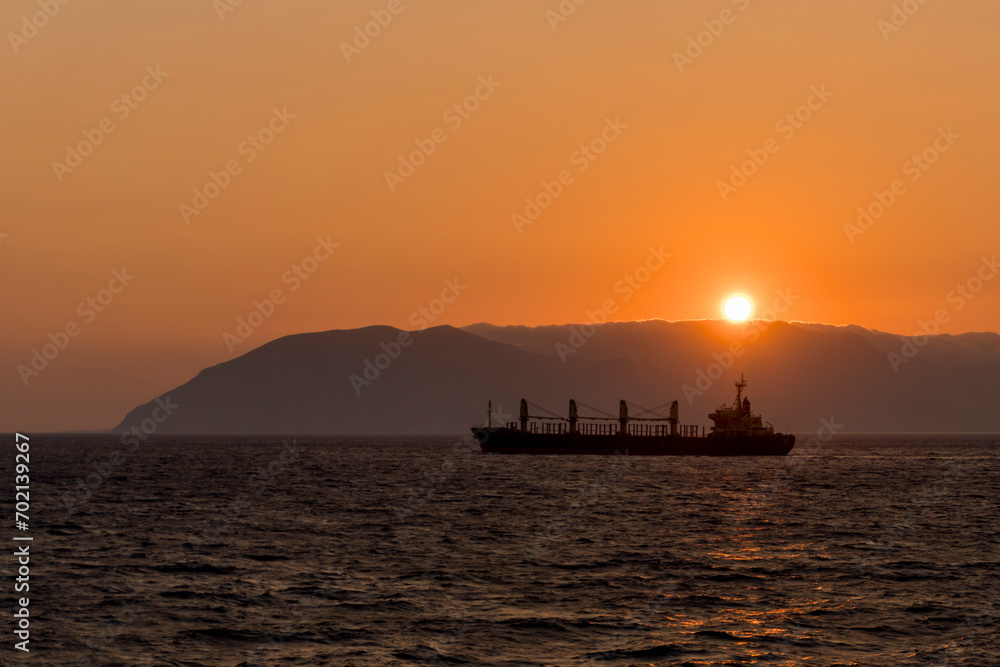 Cargo vessel at sea. Bulk carrier. Dry cargo ship at sunset. Golden hour.
