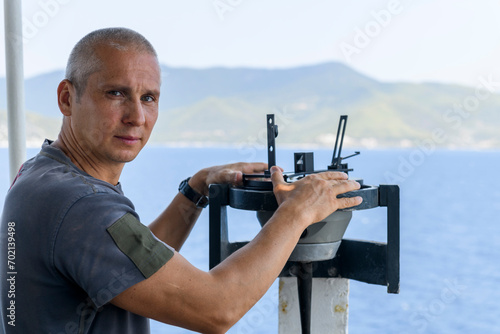 Navigational officer taking bearing with azimuth ring on gyro compass on the wing of navigational bridge. Navigational equipment usage. Observations.