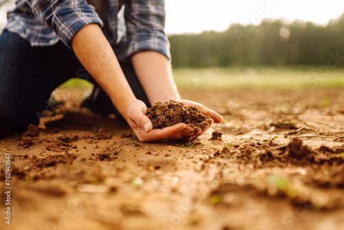 Close-up of a farmer's strong hands on a black field. The male hands of an agronomist sort through and check the quality of the soil. Concept of gardening, ecology. photo