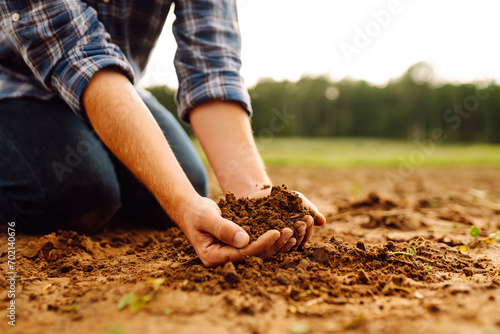 Close-up of a farmer's strong hands on a black field. The male hands of an agronomist sort through and check the quality of the soil. Concept of gardening, ecology.