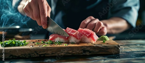 Close up Professional sushi chef hand using knife cutting Otoro Tuna belly part sashimi prepare to make perfect sushi with precision and confidence. with copy space image