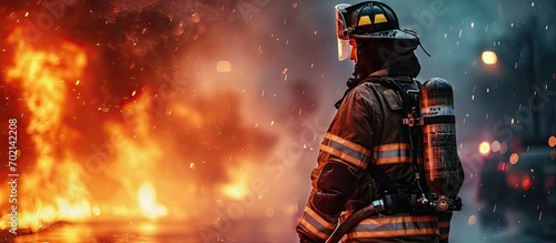 Amidst the billowing smoke the professional firefighter stands with unwavering resolve firmly gripping the fire hose ready to battle the raging inferno. with copy space image © vxnaghiyev
