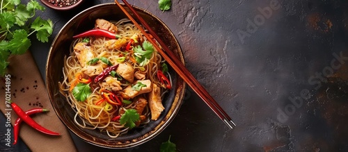 Asian noodles with chicken vegetables in bowl Asian style dinner Chinese or Japanese noodles Glass noodles stir fry with chicken carrots and onions Top view. with copy space image photo