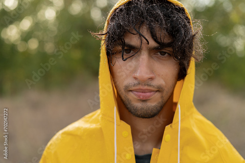 Fotografie Portrait of a muslim young wet man in a raincoat in the rain, close-up