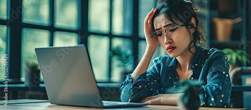 Adult asian business working woman has frustrated stressed and tried Sitting at desk and work with laptop Clear window office. with copy space image. Place for adding text or design photo