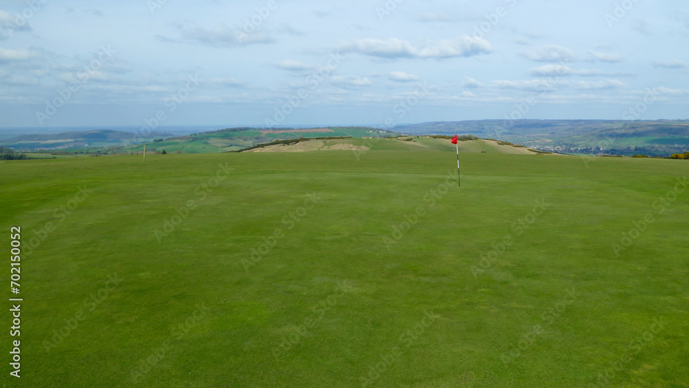 Large golf green with hole and flagstick, no trees, England, United Kingdom