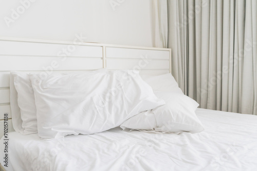 White pillow on wrinkle bed sheet in hotel room in the morning , soft focus,  concept of bedding, bedroom