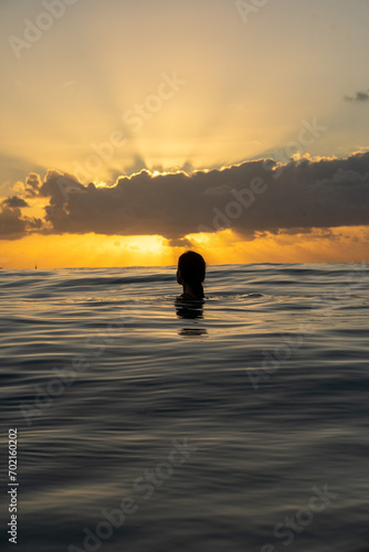 Girl inside the ocean looking at the beautiful sunrise