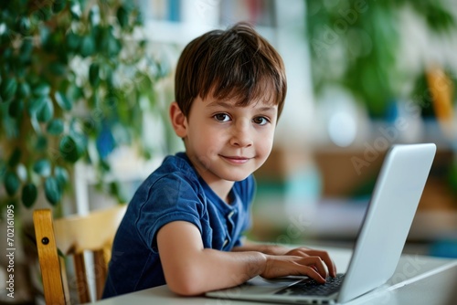 Boy sitting at the table, using the laptop for online lesson learning