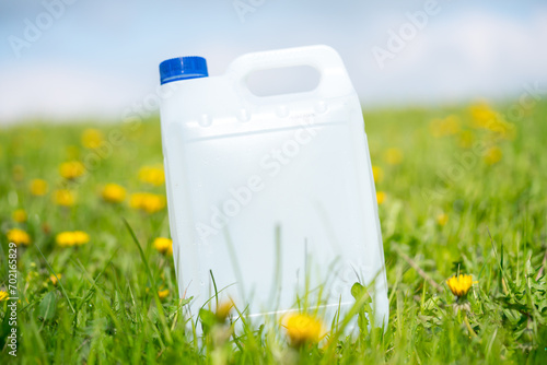 empty canister with herbicide and pesticides or fertilizers on a green meadow