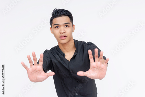 Картината върху платно A young asian man puts his hands forward, diffusing a tense situation