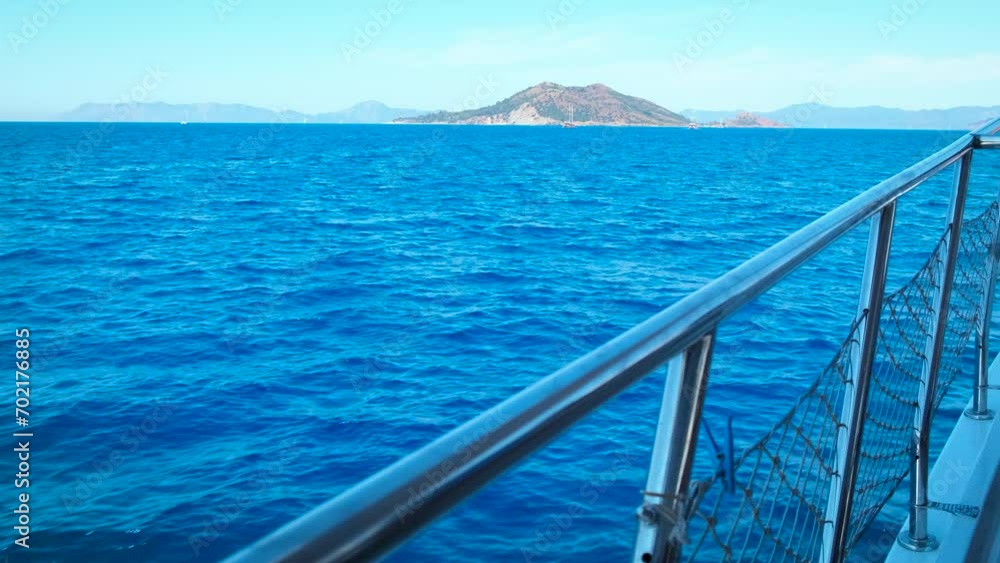 Yacht floating at picturesque morning. A view of metal yacht deck sailing in the sea with rocks during summer time. Yacht floating at picturesque morning. A view of metal yacht deck sailing in the sea with rocks during summer time.