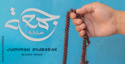 Jummah Mubarak blessed happy Friday Arabic calligraphy, Selective focus image hand of Muslim woman holding prayer beads. photo