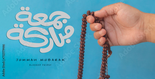 Jummah Mubarak blessed happy Friday Arabic calligraphy, Selective focus image hand of Muslim woman holding prayer beads. photo
