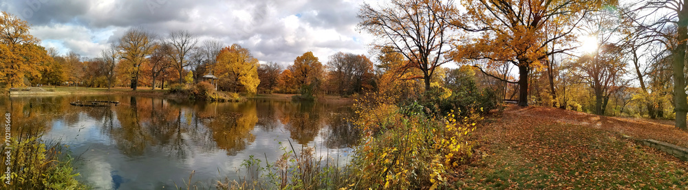 European park and pond in autumn. Atmospheric nature panorama photo.