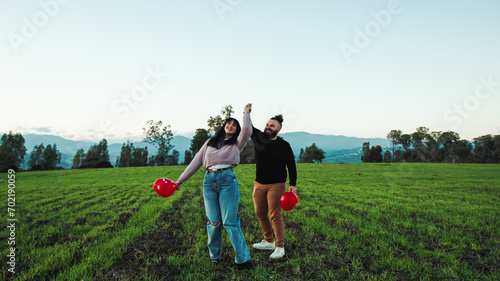 Engaged couple in the field with red balloons