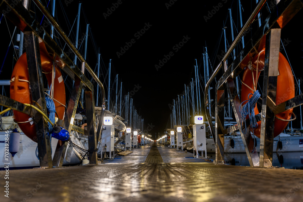 Yacht marina quay at night time. Mediterranean yacht port with sailing boats. Darkness. Calm weather. Yachting concept.