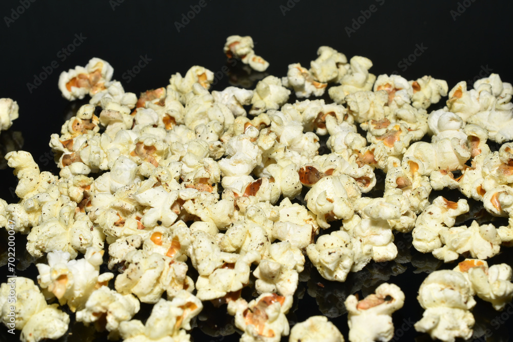 Popcorn lies in a pile on a dark background. Popcorn lies in a pile on a dark background.