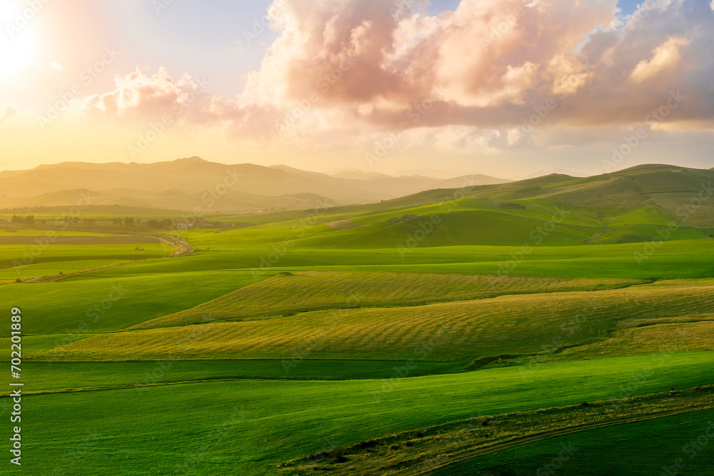 beautiful green valley with green fields with green spring grass with nive hills and mountains and scrnic colorful cloudy sunset on background of landscape