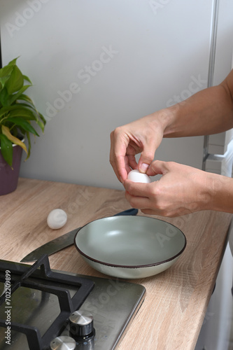 woman breaks eggs to make an omelette.