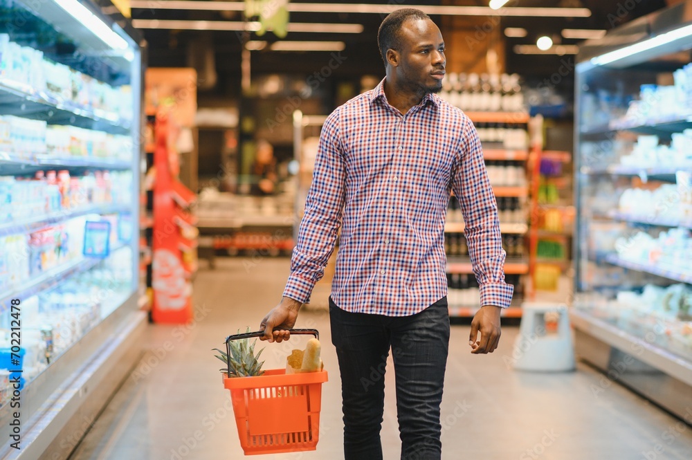 African man shopping at supermarket. Handsome guy holding shopping basket