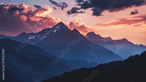 Sunset over snow-capped mountains and green forest with dramatic clouds