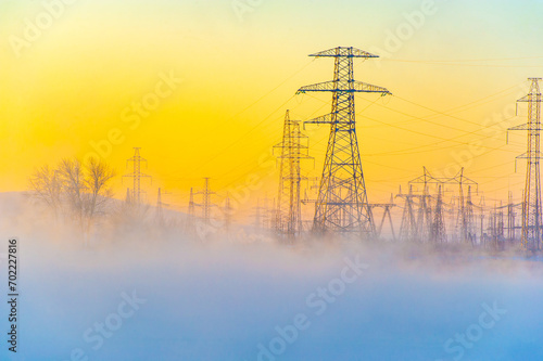 Beautiful and atmospheric scene of a winter morning. High voltage power lines add an element of power and energy. The misty fog adds a sense of mystery and tranquility.