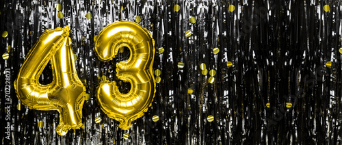Gold foil balloon number number 43 on a background of black tinsel decoration. Birthday card, inscription forty-three. Anniversary event. Banner.