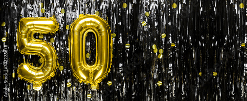 Gold foil balloon number number 50 on a background of black tinsel decoration. Birthday greeting card, inscription fifty. Anniversary event. Banner.