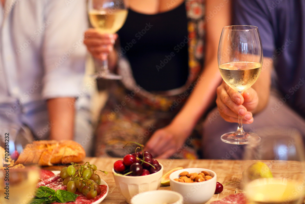 Hands of a group of people cheering with white wine