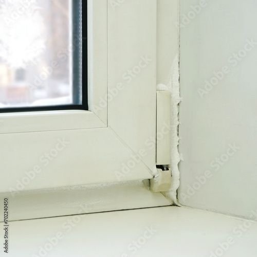 Not hermetic window frame snow covered freezing inside the room during severe frost. Close-up of a frozen defective plastic window in a room in winter.
