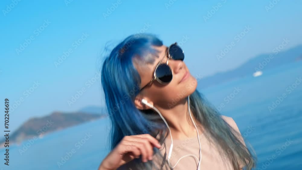 Stylish teen with dancing music in sun. A blue stylish teen girl listen the music and dance on the beach during summer vacation. Stylish teen with dancing music in sun. A blue stylish teen girl listen the music and dance on the beach during summer vacation.