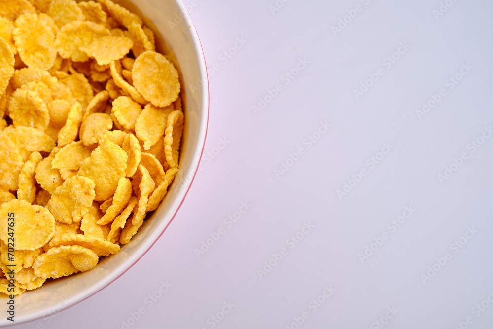 Corn flakes in a red bowl on a white background. Delicious sweet breakfast. Nutrition and health concept Corn flakes in a red bowl on a white background. Delicious sweet breakfast. Nutrition and health concept