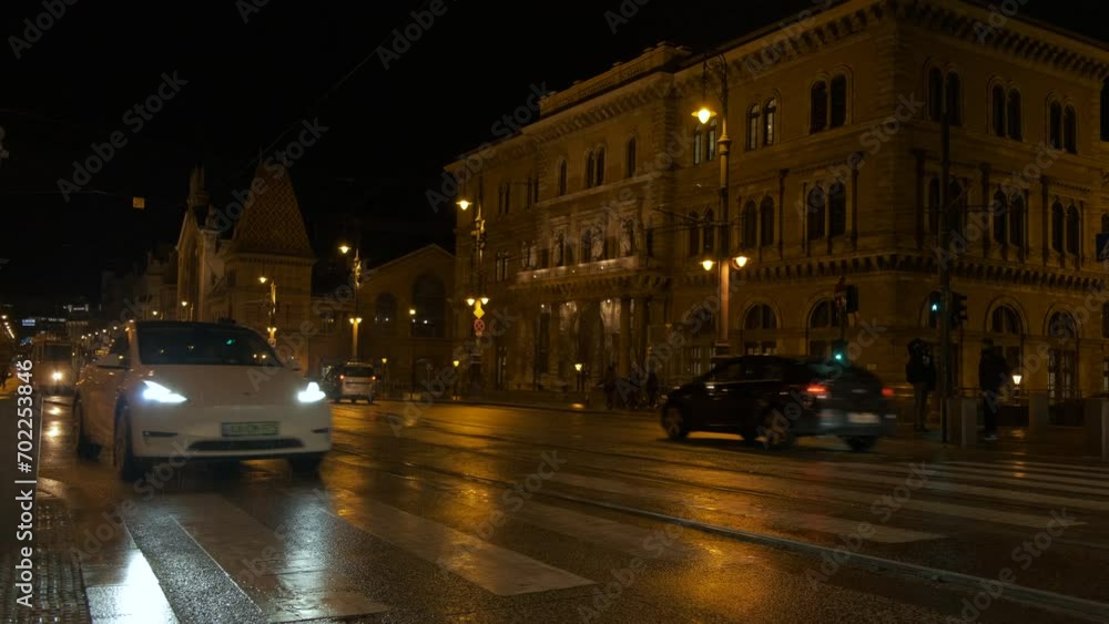 Busy traffic and citizens in budapest street. A busy cars traffic in the night street against Budapest architecture in the night. Busy traffic and citizens in budapest street. A busy cars traffic in the night street against Budapest architecture in the night.