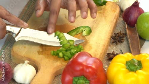 Slicing green peppers on a cutting board by the hands of a chef to prepare a delicious food.