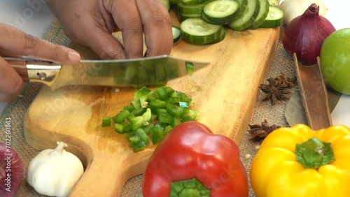 The cook cuts fresh green peppers on a cutting board to prepare a vitamin salad.