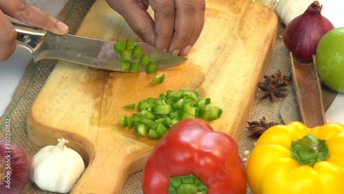 The cook cuts green peppers on a cutting board to prepare a vitamin salad.
