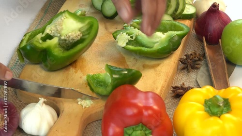 Woman cutting vegetables in the kitchen, slicing green bell pepper
