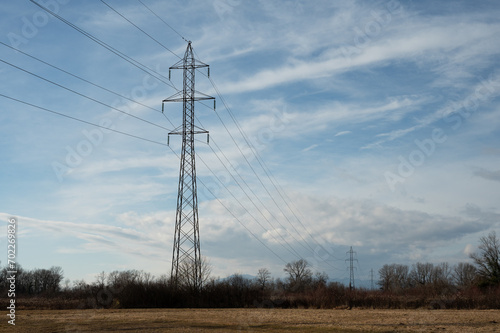 High-voltage direct current transmission. High voltage structures in the open field. Electric power line with blue sky in background.