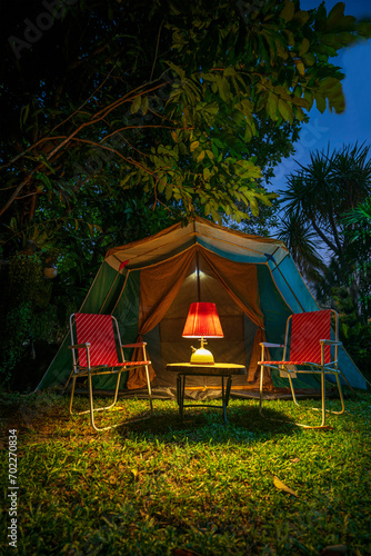 vintage cabin tent,  Antique oil lamp on a wooden table with retro chairs. at night in the  forest