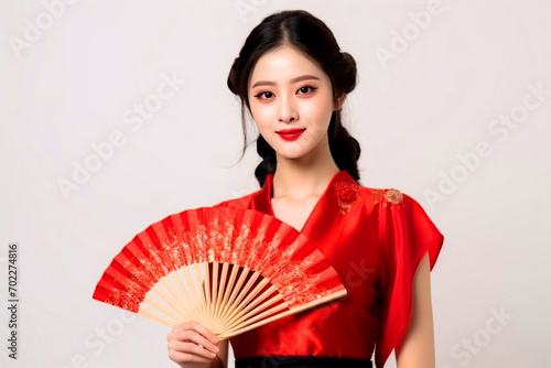 Beautiful Chinese woman in red traditional dress with fan on white background
