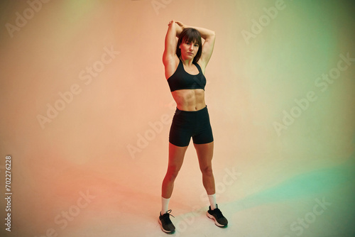 Warm up exercises. Young woman in fitness clothes is in the studio