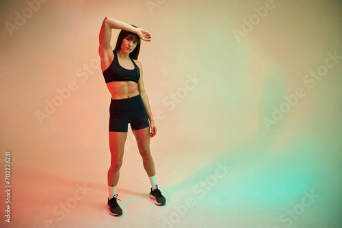 Standing and doing exercises. Young woman in fitness clothes is in the studio