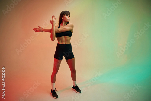 Standing and doing exercises. Young woman in fitness clothes is in the studio © standret