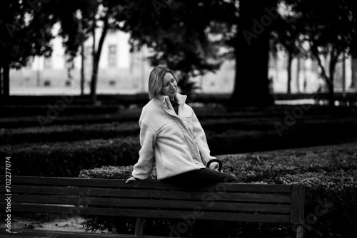 Woman sitting on a bench in a park. Black and white photo.