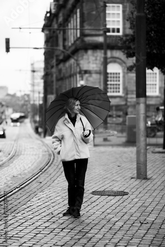 A woman with an umbrella walking in the street. Black and white photo.