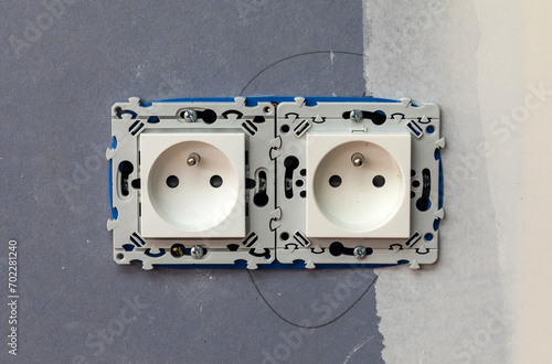 Two-slot electrical outlet socket installation on blue wallboard