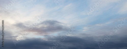 Fototapeta Naklejka Na Ścianę i Meble -  Dark and light clouds in the blue sky lit by the evening sun